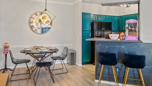 A modern kitchen with teal cabinets, a black refrigerator, and a bar area with two blue bar stools. - Kid Friendly 2-bedroom condo in Scottsdale with Pool, Hottub, fitness room, WiFi (Scottsdale)