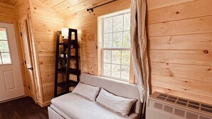 A wooden cabin room with a bed, a ladder, a window, and a heater. - Green Cabin in Surry close to Acadia and Bar Harbor (Surry)