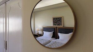 Ein Hotelzimmer mit zwei Betten, einem Nachttisch, einer Lampe und einem gerahmten Kunstwerk an der Wand.