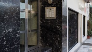 Ein Hotel mit Eingang, einer Glastür, einer Marmorfassade und einem Schild, das Zimmerverfügbarkeit anzeigt.