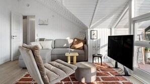 A modern living room with a sofa, ottoman, and a TV. - 2 bedroom beautiful home in Børkop (Børkop)