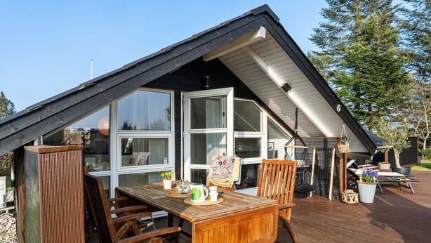 A wooden deck with a table and chairs, a large window, and a small garden area with plants. - 2 bedroom beautiful home in Børkop (Børkop)