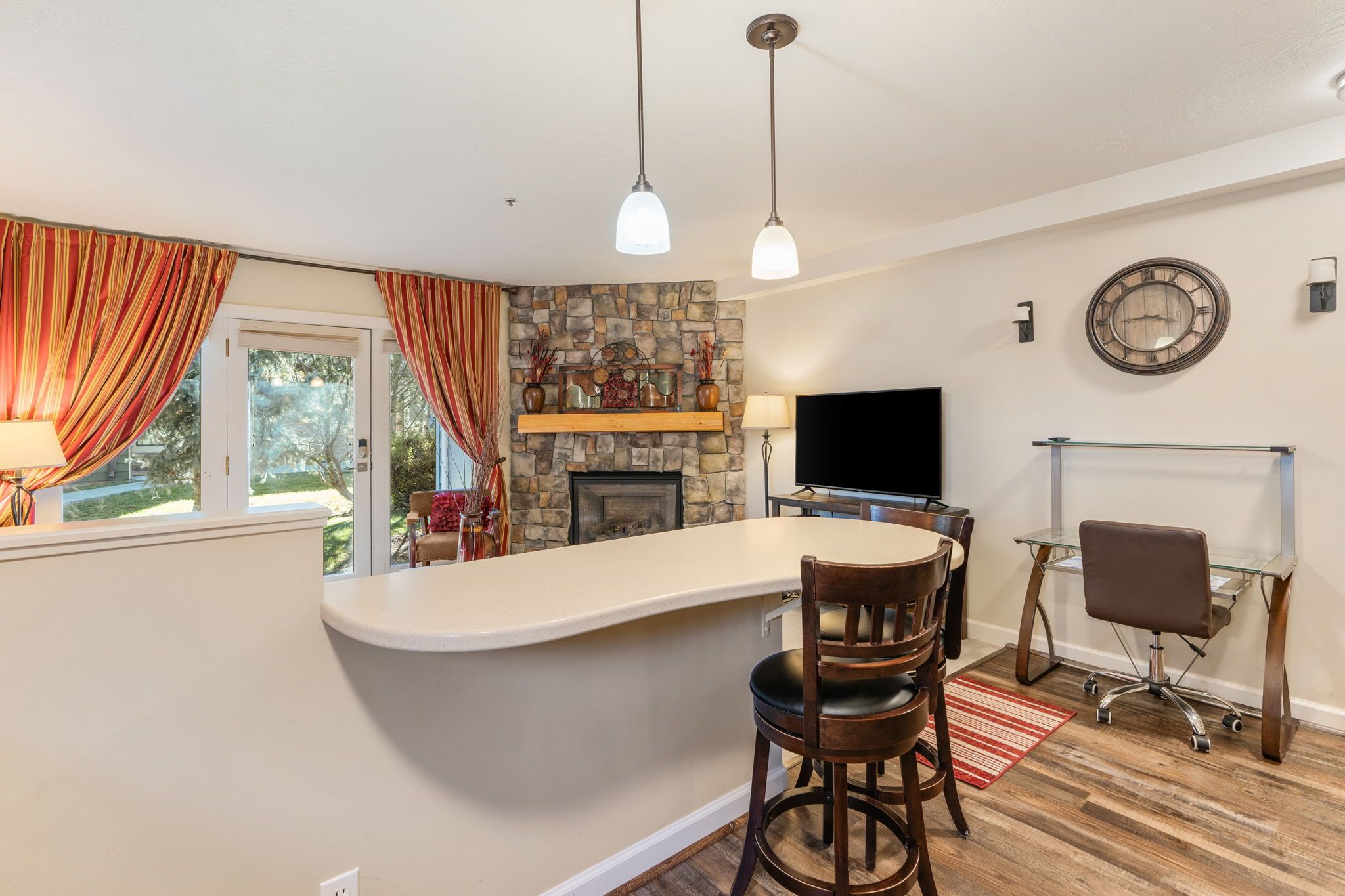 Una cocina con pared de piedra, chimenea, barra y zona de comedor con sillas y televisor.