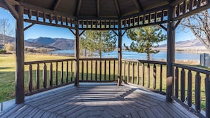Un mirador con piso de madera y barandillas, con vista a un lago y montañas.