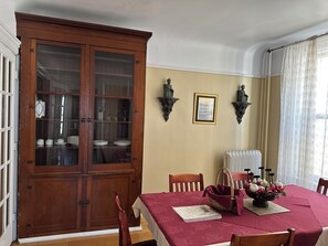 A dining room with a wooden cabinet, a table with a red tablecloth, and two wall-mounted sconces. - Spacious Historic Victorian  Apt , Steps to Saint John Boardwalk & landmarks (Saint John)