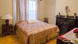 Un dormitorio con cama, mesita de noche, lámpara, cómoda y ventana con cortinas.