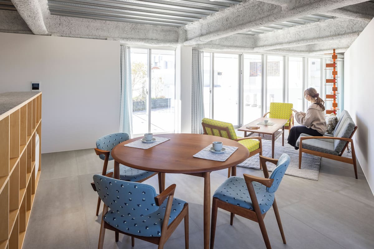 Un intérieur moderne avec une table ronde en bois, des chaises à motifs bleus, un canapé et un escalier.