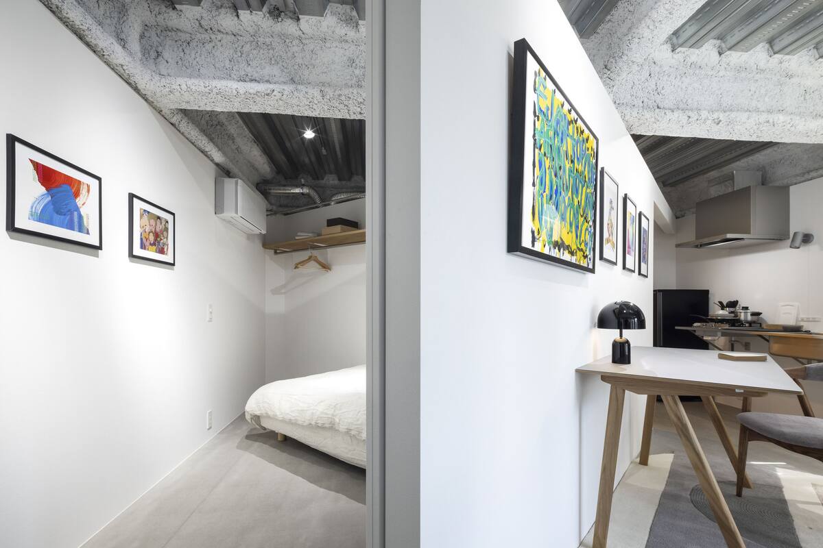 Une chambre moderne avec un lit, un bureau et des œuvres d’art accrochées aux murs.