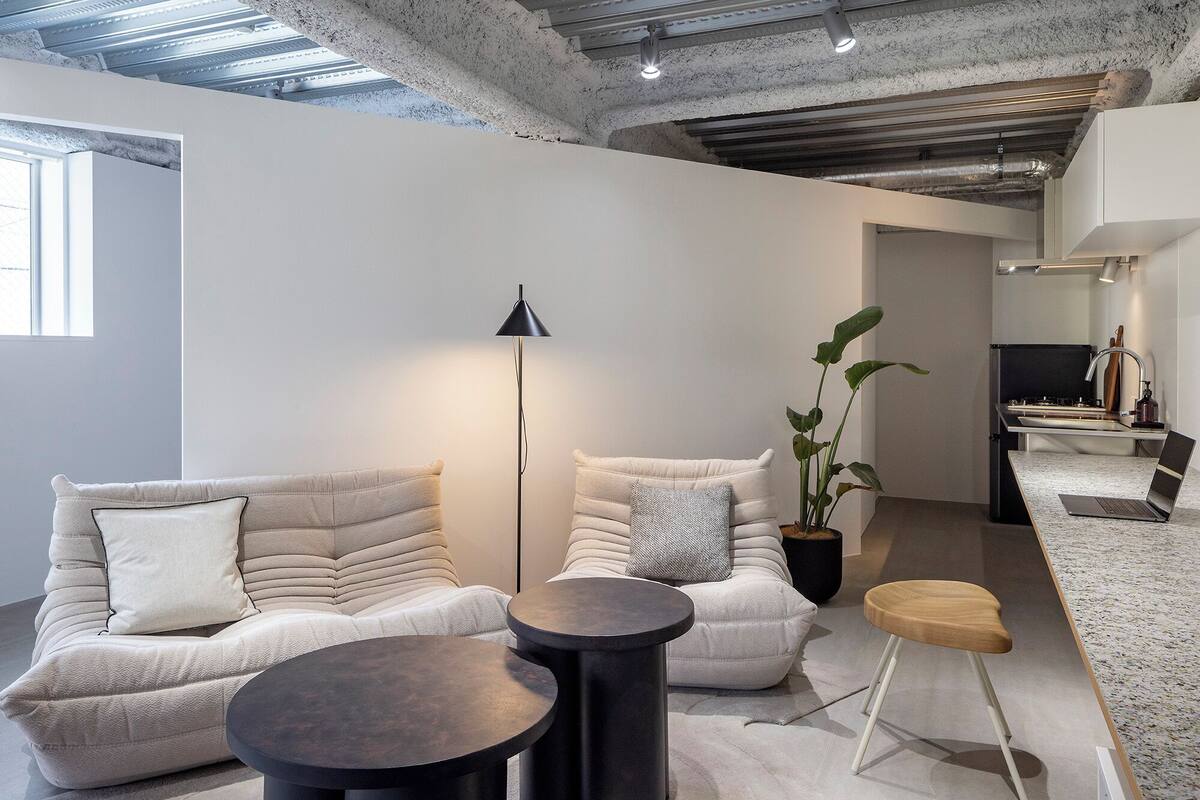 Un salon moderne avec un canapé, deux tables d’appoint, une lampe sur pied et une plante.