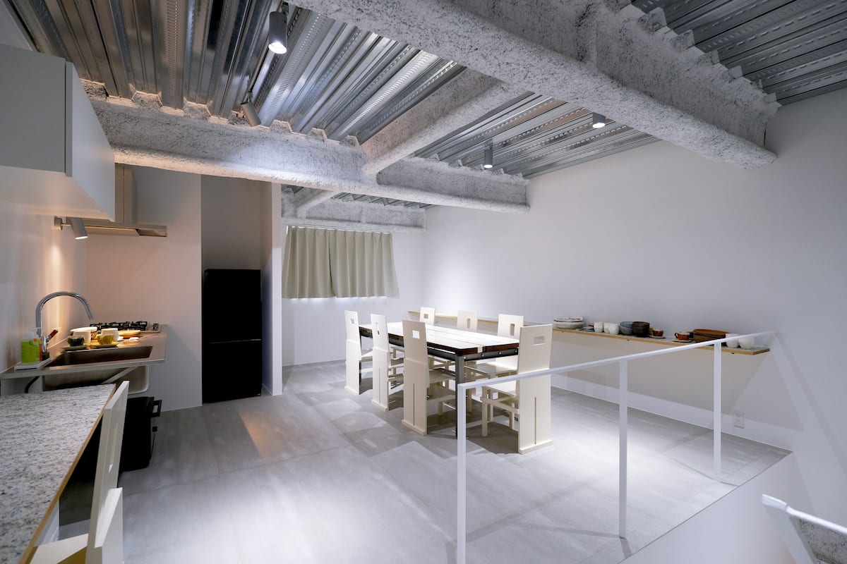Une cuisine moderne avec des meubles blancs, un plan de travail en granit et un coin repas comprenant une table et des chaises blanches.