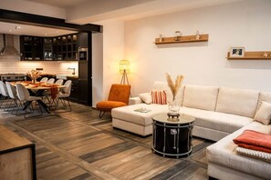 Una sala moderna con comedor, un sofá, un taburete tipo tambor y una lámpara.