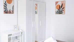 Um quarto com uma cama, uma escrivaninha e um guarda-roupa.