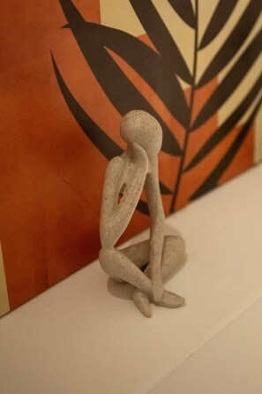 Escultura de una figura sentada sobre una superficie blanca.