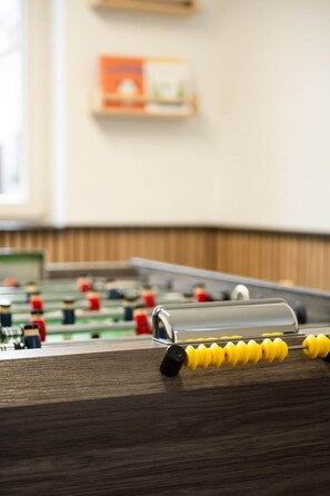 Una mesa de fútbolín con tablero de madera y figuras de jugadores amarillas y rojas.