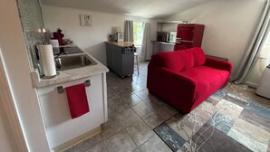 A compact living space with a kitchenette, a red sofa, and a patterned rug. - Charming 1-bedroom apartment with AC, WiFi in beautiful Fairport (Fairport)