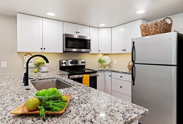 Enjoy cooking in this fully equipped kitchen with a microwave, oven, refrigerator, sink, and cutting board.