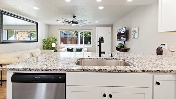 A modern kitchen with granite countertops, a dishwasher, and a ceiling fan. - Cozy Boise Stay: Central Spot (Boise)