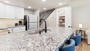 A modern kitchen with granite countertops, white cabinets, a built-in refrigerator, and a black faucet. - Cozy Boise Stay: Central Spot (Boise)