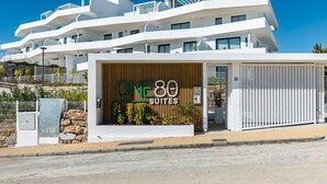Un hotel moderno de varios pisos con un letrero llamativo que dice 'ONE80 SUITES'.