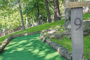 A green artificial turf golf course with a stone border and a wooden sign with the number 9.