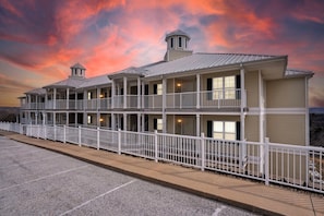 A multi-story hotel with a balcony, a covered walkway, and a parking lot.