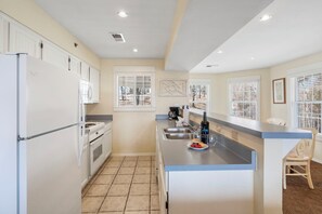 A modern kitchen with white cabinets, a central island, and a view of the outdoors through windows. - Inviting Lakeview Condo with Firepit Table, Outdoor Pool, Table Rock Access & Free Daily Tickets (Kimberling City)