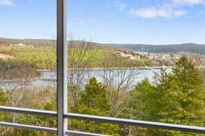 A view from a window overlooking a lake with buildings in the distance and trees in the foreground. - Inviting Lakeview Condo with Firepit Table, Outdoor Pool, Table Rock Access & Free Daily Tickets (Kimberling City)