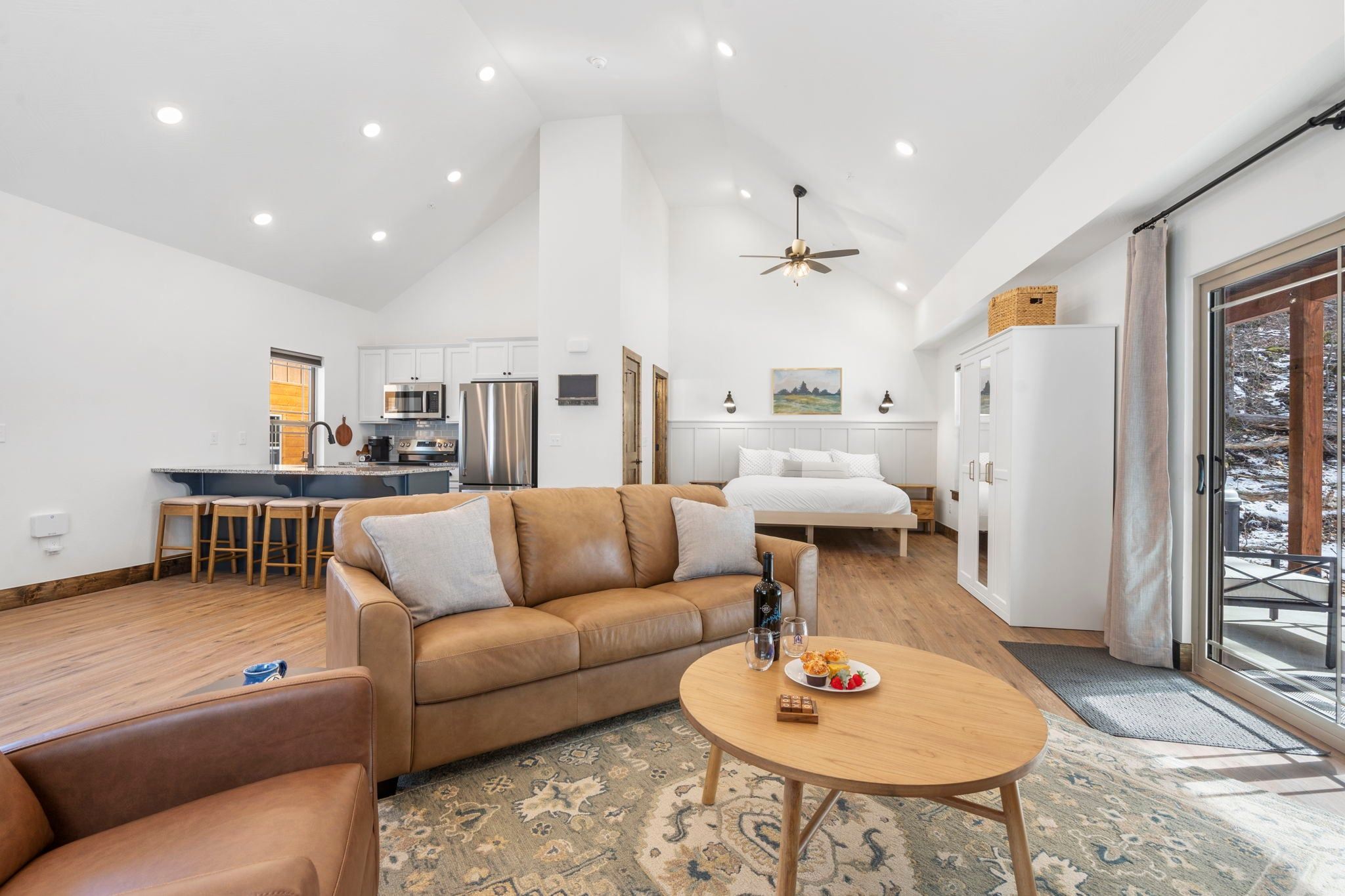 A modern living room with a leather sofa, a round coffee table, and a dining area with a small table and chairs.