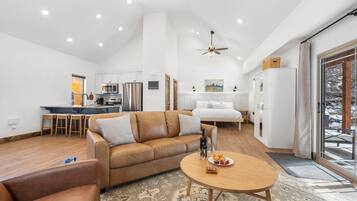 A modern living room with a leather sofa, a round coffee table, and a dining area with a small table and chairs.