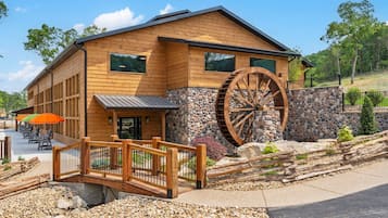 A wooden building with a large water wheel, a stone wall, and a wooden bridge.