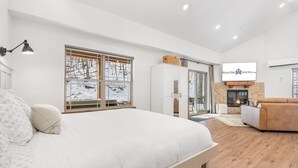 A modern bedroom with a large bed, a fireplace, and a television.