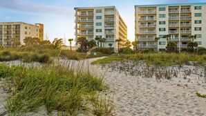 Un hôtel situé en bord de mer, doté de nombreux balcons et d’une promenade bordée de sable.