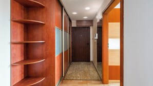 Un couloir avec des étagères en bois, un sol recouvert de moquette et une porte en bois au fond.