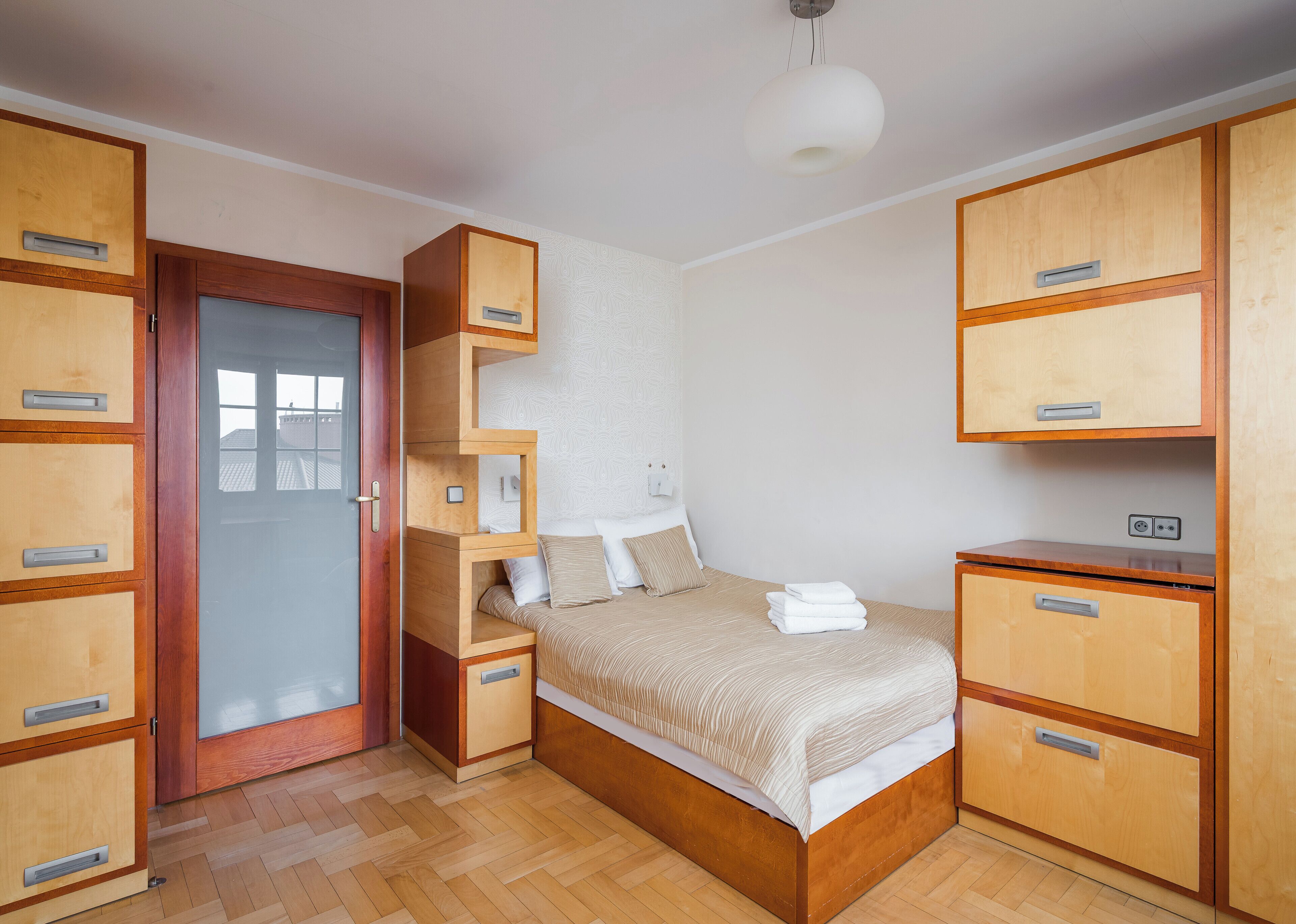 Ein Schlafzimmer mit Bett, Holzschränken, einem Kleiderschrank und einer Tür.