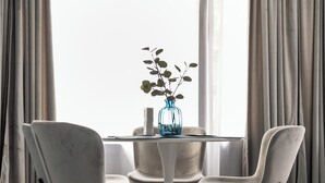 Uma sala de jantar com uma mesa redonda, quatro cadeiras e um vaso com uma planta.