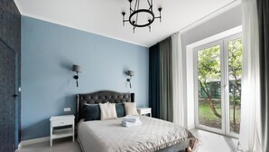 Quarto com uma cama grande, duas mesas de cabeceira, um candelabro e vista para o exterior.