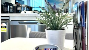 A modern kitchen with a potted plant, a bowl of snacks, and a microwave.