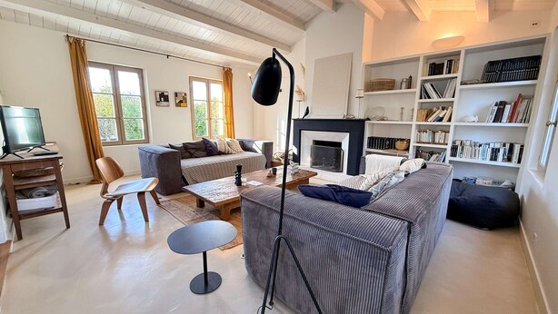 A cozy living room with a fireplace, a sofa, a coffee table, and a bookshelf.