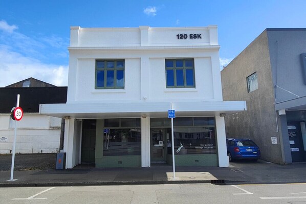 Un bâtiment à deux étages, situé au 120 ESK, avec une enseigne indiquant « New Zealand Heritage Properties ».