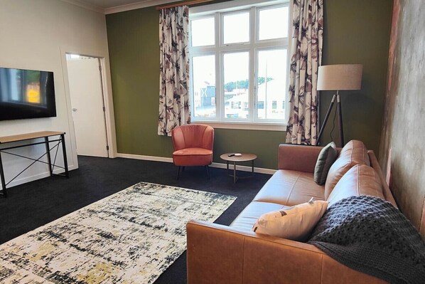 Un salon comprenant un canapé, un fauteuil, une table basse et un téléviseur à écran plat.