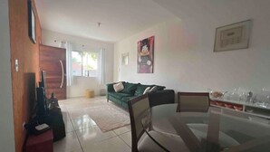 Un soggiorno moderno con un tavolo da pranzo in vetro, un divano verde e un armadio in legno.