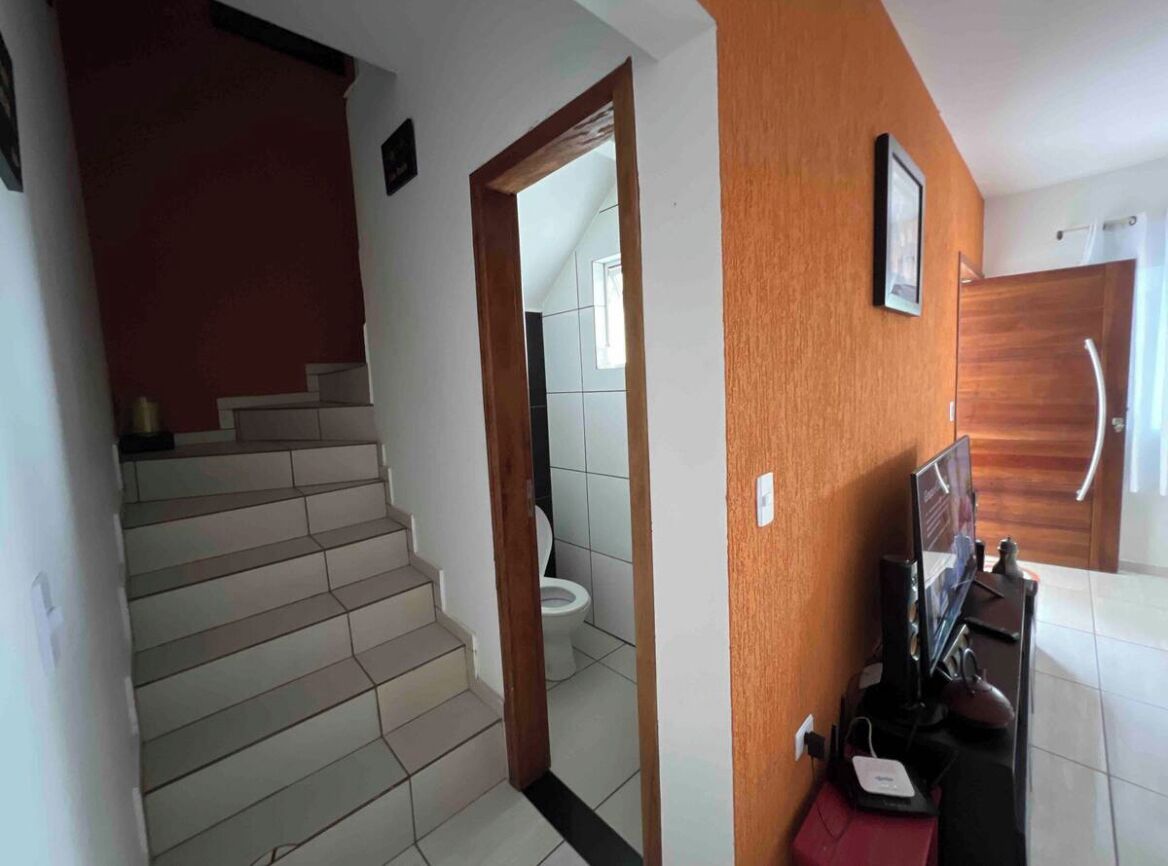Eine Treppe führt zu einem Badezimmer mit Toilette und Duschbereich.