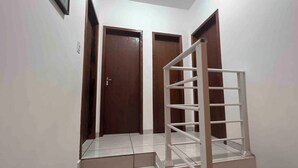 Una scala con ringhiera in metallo che conduce a un pianerottolo, una porta e un quadro appeso al muro.