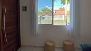 Una stanza con una porta in legno, una finestra con tende bianche e due poltrone sacco color beige.