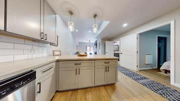 A modern kitchen with light wood cabinets, a central island, and pendant lighting.