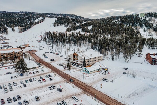 A ski resort with multiple buildings, a parking lot, and a snow-covered landscape.