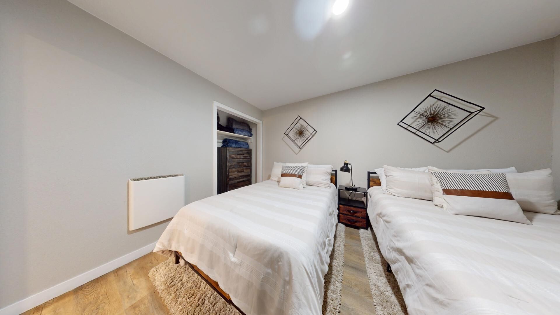 Un dormitorio con dos camas, un radiador, un armario y una puerta que da a un baño.