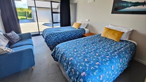 Une chambre d’hôtel avec deux lits, un canapé et une porte-fenêtre coulissante donnant sur un balcon.