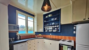 A kitchen with white cabinets, a stove, a microwave, and a sink. - Riverton Beachhouse View (Riverton / Aparima)