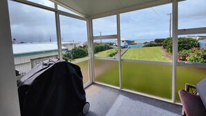 A room with large windows, a covered grill, and a view of a green lawn and buildings.